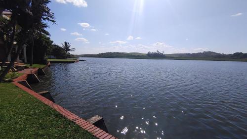 a large body of water with trees and grass at THE BOAT HOUSE, 53 Nkwazi Drive in Zinkwazi Beach