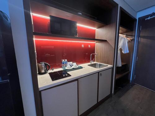 a small kitchen with a sink and a red wall at Lighthouse Apec Mũi Né in Phan Thiet