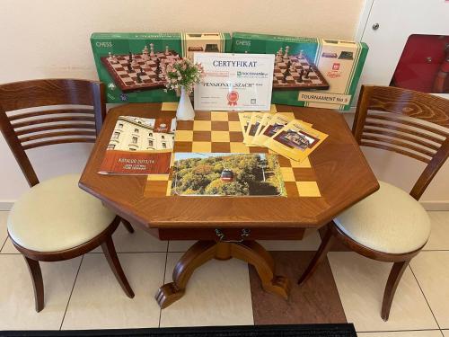 a table with a chess board on it with two chairs at Pensjonat Szach in Krynica Zdrój