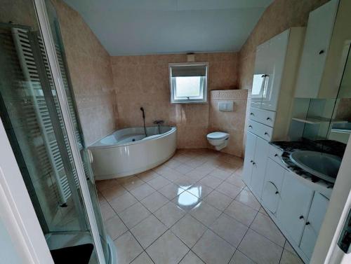 een badkamer met een bad, een toilet en een wastafel bij Chalet Anloo, van harte welkom. in Anloo