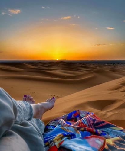 a person laying in the desert watching the sunset at Desert Berber Fire Camp in Merzouga