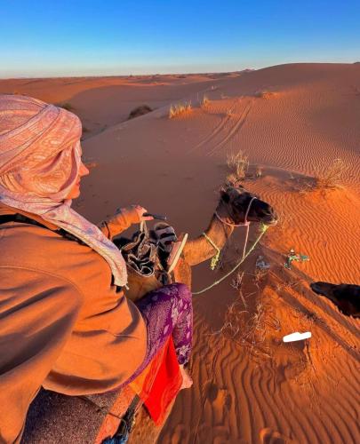 a woman sitting on a rock in the desert at Desert Berber Fire Camp in Merzouga