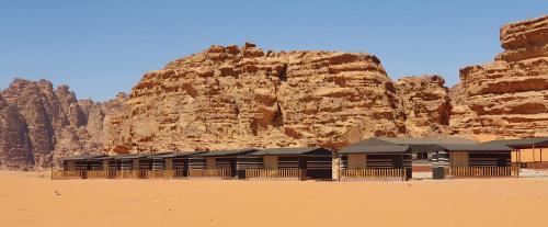 a building in the desert next to a mountain at Rum Under The Stars Camp in Wadi Rum