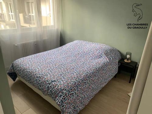 a bed in a room with a bedspread on it at Les chambres du Graoully - Le 136 - Metz Queuleu - Place de parking intérieur in Metz