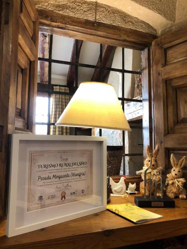a lamp sitting on a desk next to a framed picture at Posada Real Mingaseda in Navafría