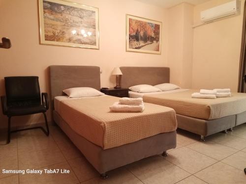 a room with two beds and a chair in it at VILLA AVATOS - Near to the Port of Rafina and the Airport of Athens in Áyios Spirídhon