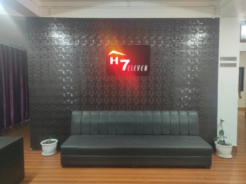 a black couch in a room with a clock on a wall at Hotel 7 Eleven in Dirang Dzong