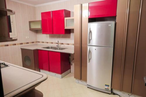 eine Küche mit roten Schränken und einem Kühlschrank aus Edelstahl in der Unterkunft The Villa 604 Powered by look in Kairo