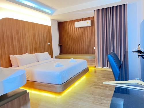 Cette chambre comprend un lit blanc et des chaises bleues. dans l'établissement โรงแรม ชม เชียงราย, à Ban Hua Khwai (1)