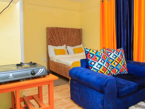 a living room with a blue chair and a bed at BASICS HOME STAYS in Nairobi