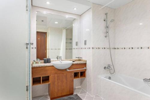 een badkamer met een wastafel, een bad en een spiegel bij StoneTree - Amazing 1BR with Lake View in Dubai