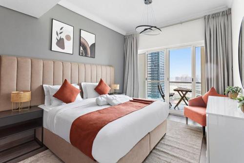 een slaapkamer met een groot bed en een groot raam bij StoneTree - Amazing 1BR with Lake View in Dubai