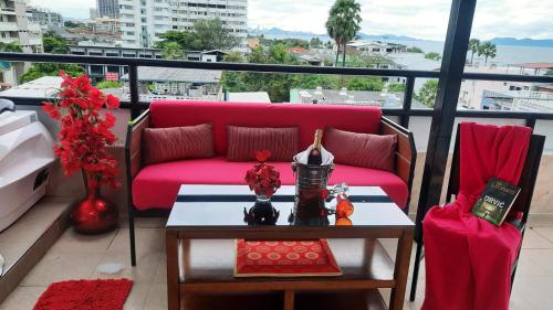 a living room with a red couch on a balcony at Happy Beach Jomtien Guesthouse in Jomtien Beach