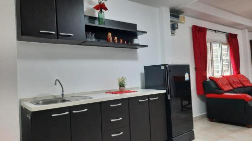 a kitchen with a sink and a black refrigerator at Happy Beach Jomtien Guesthouse in Jomtien Beach
