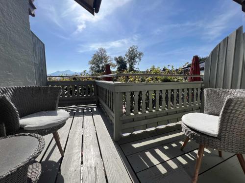 a wooden deck with chairs and a fence at Sieben Zimmer am See in Prien am Chiemsee