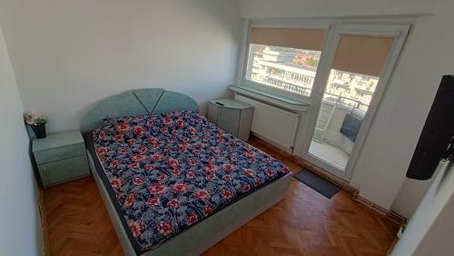 a bedroom with a bed with a flowered blanket and two windows at ALBA IULIA Cetatea Alba Carolina in Alba Iulia