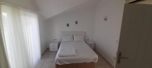 een kleine witte kamer met een bed en een raam bij Sea Villa Apart in Fethiye