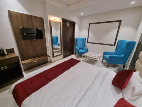 een hotelkamer met een bed en twee blauwe stoelen bij LUXE RESORTS - CENTRALLY HEATED AIR CONDITIONED HOTEL in THE HEART OF KASAULI in Kasauli