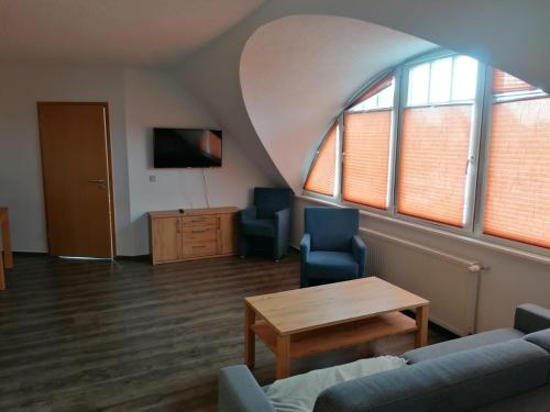 a living room with a couch and a table and windows at Ferienwohnungen Ryck Blick in Greifswald