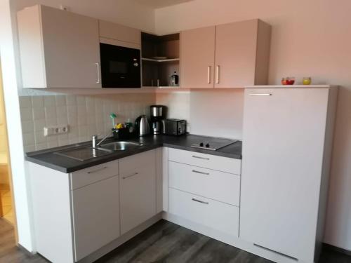 a kitchen with white cabinets and a sink at Ferienwohnungen Ryck Blick in Greifswald