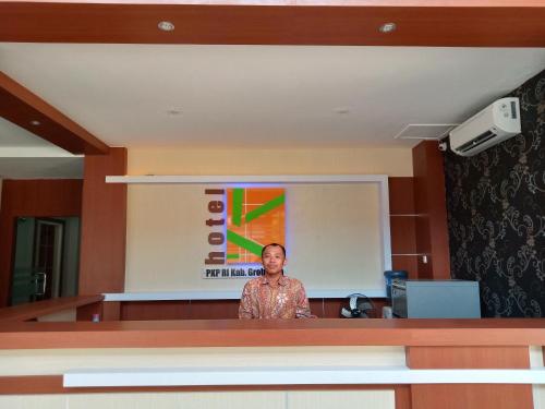 a woman standing in front of a podium at Karunia Hotel in Purwodadi