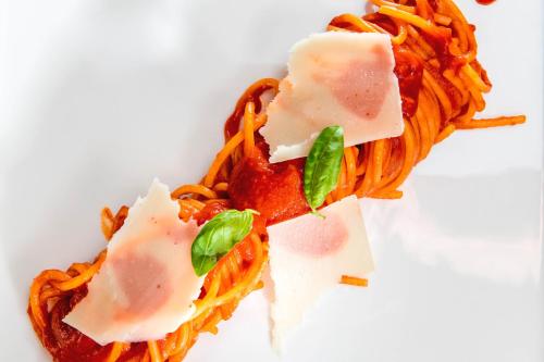 a plate of spaghetti with cheese and sauce at Hotel La Ville Rome in Rome