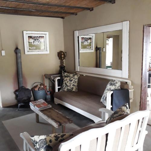 a living room with a couch and a mirror at Saffier river cottage Farmstay in Lady Grey