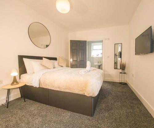 a bedroom with a large bed and a mirror at Principality Suites - Two Bed Apartment by Property Promise in Cardiff