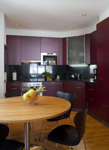 a kitchen with purple cabinets and a wooden table with a bowl of fruit at Apartments Residenz Iris in Leukerbad