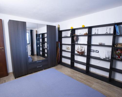 Zimmer mit schwarzen Regalen und einer Tür mit blauem Teppich in der Unterkunft Appartamento sul mare in Su Forti