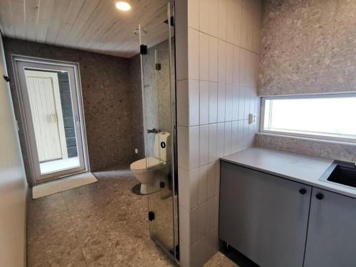 La salle de bains est pourvue de toilettes, d'un lavabo et d'une fenêtre. dans l'établissement Villa Sudenkolo with outdoor jacuzzi and log sauna, à Syöte
