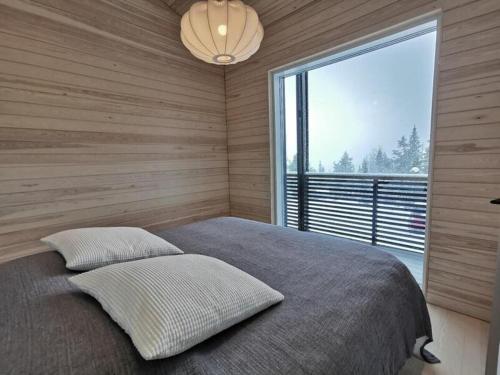ein Schlafzimmer mit einem Bett und einem großen Fenster in der Unterkunft Villa Sudenkolo with outdoor jacuzzi and log sauna in Syöte