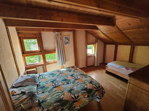 ein Schlafzimmer in einem Blockhaus mit einem Bett und Fenstern in der Unterkunft Belle maison Vue imprenable lac de Serre-Ponçon in Prunières