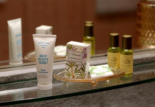 a counter with three bottles of moisturizing moisturizers and a tray oficating cosmetics at HR Hotel in Monfalcone