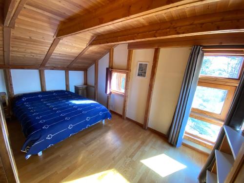a bedroom with a blue bed in a room with windows at Belle maison Vue imprenable lac de Serre-Ponçon in Prunières