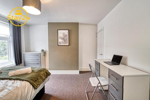 a bedroom with a bed and a desk with a laptop at Cosy Carlton in Stoke on Trent