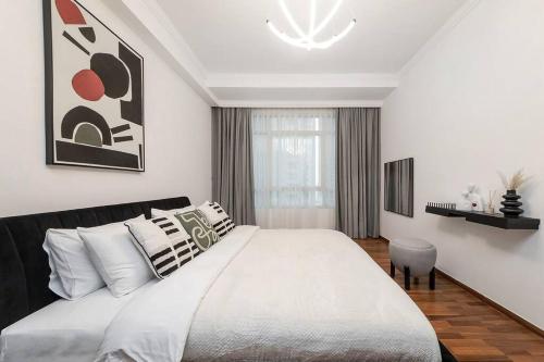 a white bedroom with a large bed and a chair at Spacious 2BR apartment in Marina Crown in Dubai