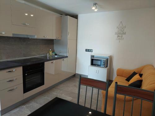 a kitchen with an orange couch and a microwave at Apartma Žirovnik in Cerklje na Gorenjskem