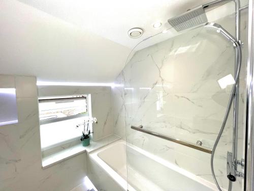 a white bathroom with a shower and a sink at Luxury Architect Designed Town House Near Beach in Littlehampton