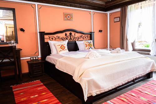 a bedroom with a large bed with orange walls at Къща ЕТНО in Koprivshtitsa