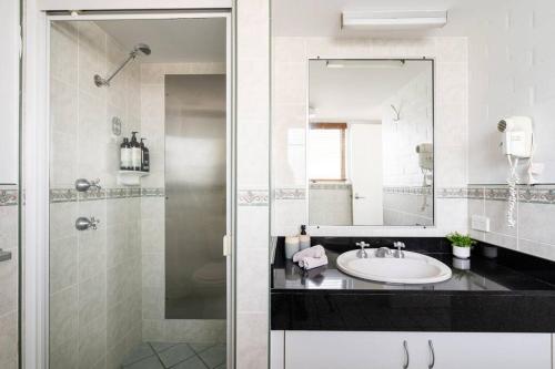 a bathroom with a sink and a shower with a mirror at Haven on Noosa Hill - sunset views, pools, spa in Noosa Heads