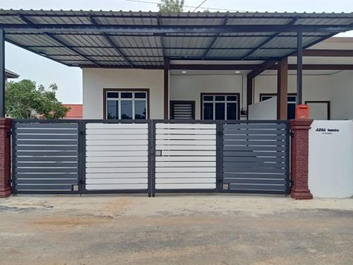 a garage with blue and white gates and a building at ADSA homestay in Kampong Wakaf Tengah