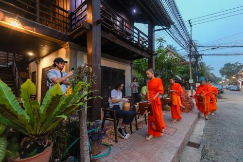 a group of people in orange robes standing outside a building at Ancient Luangprabang Hotel in Luang Prabang