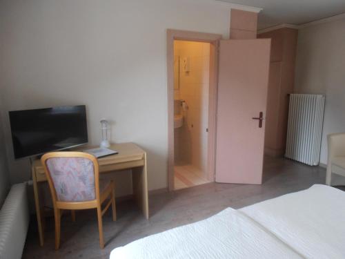 a bedroom with a desk with a computer and a chair at Hotel Restaurant Escher in Leukerbad