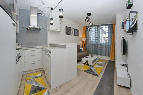une cuisine avec des placards blancs et un salon dans l'établissement Cable Car Apartment Baščaršija, à Sarajevo