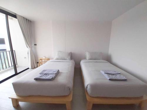 two twin beds in a room with a window at Tassanaplace Boutique Hotel (ฺBansuan) in Chon Buri
