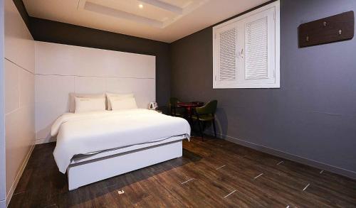 1 dormitorio con cama blanca y mesa en Motel Lamant en Bucheon