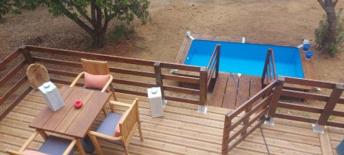 une terrasse en bois avec une table et des chaises ainsi qu'une piscine dans l'établissement Chalets du golfe de st Tropez l olivier, à La Garde-Freinet