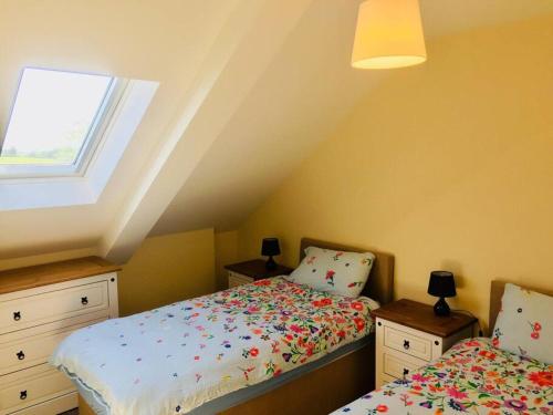 a attic bedroom with two beds and a window at Mourne Views 2 Bed Apartment in Kilkeel