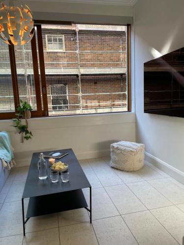 a living room with a table and a window at Stylish apartment in the heart of Potts Point in Sydney
